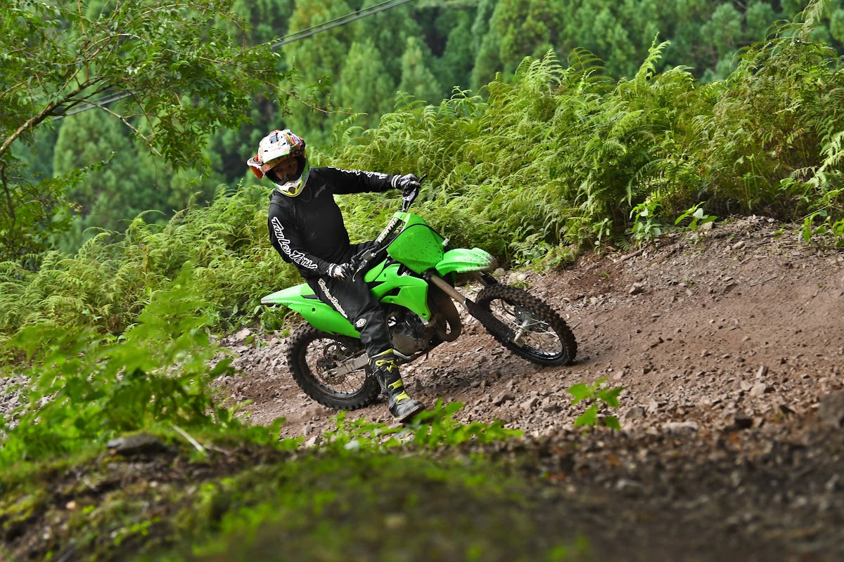 緑のオフロードバイクでコーナーを走るライダー