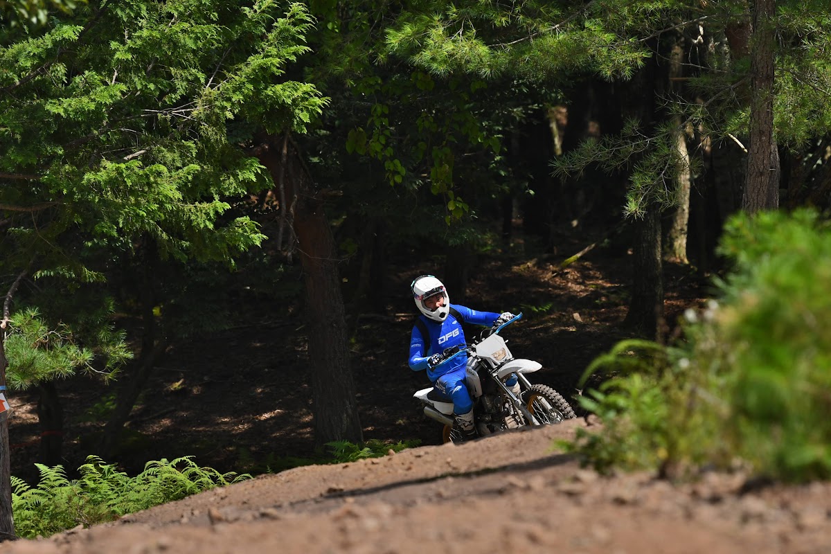 森の斜面を登る青いウェアのライダー